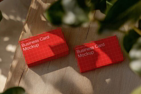Red business card mockup with grid pattern on wooden surface ideal for graphic designers realistic shadow effect branding template digital asset