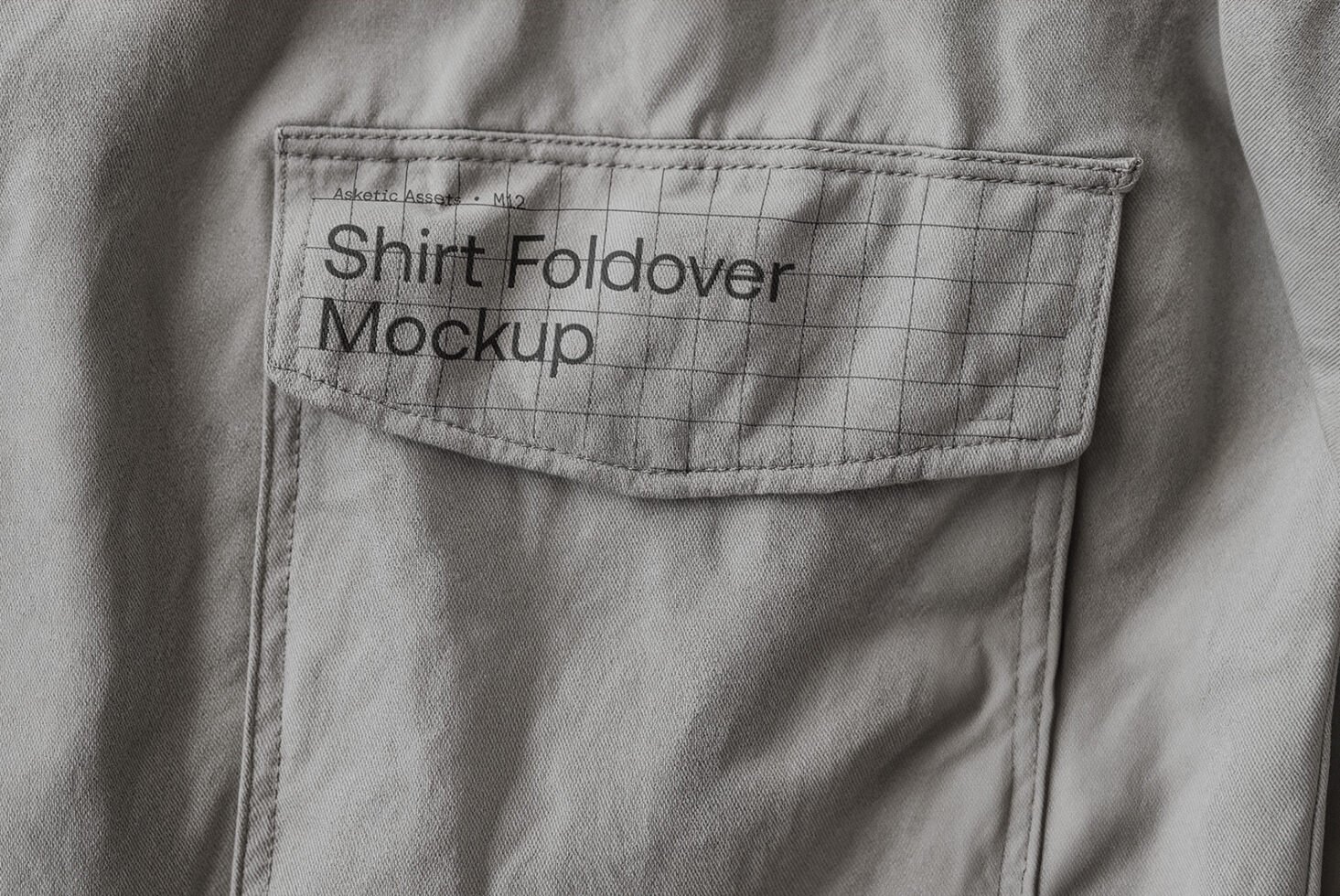 Close-up of a gray shirt foldover with label saying Shirt Foldover Mockup with grid pattern. Perfect for showcasing apparel branding and design templates.