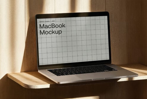Laptop mockup on wooden shelf showcasing grid design screen with sunlight shadows ideal for designers searching mockup templates digital assets.
