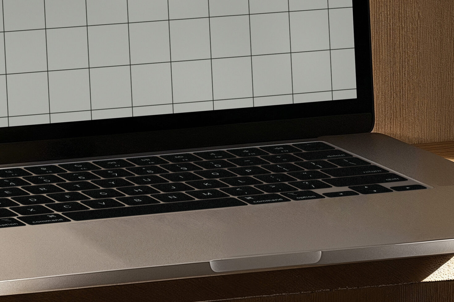 Laptop keyboard close-up with screen displaying blank grid for mockup templates. Ideal for designers looking for digital design assets and resources.