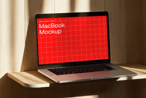 MacBook mockup on wooden surface with red grid screen design. Ideal for showcasing UI templates and digital assets for designers seeking quality mockups.