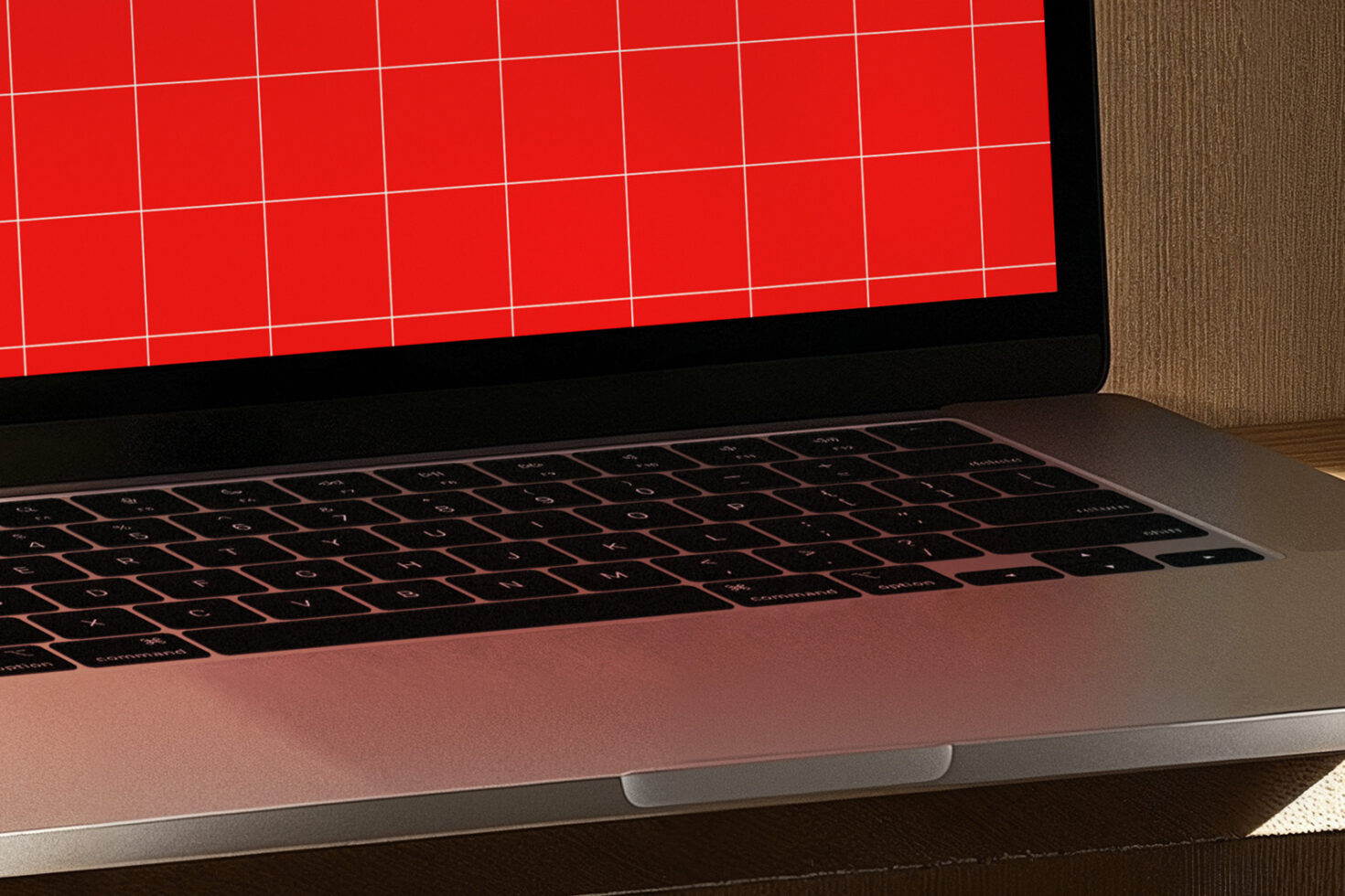 Laptop close-up with red grid screen for mockup and design templates. Ideal for digital designers, showcasing technology and workspace setup.
