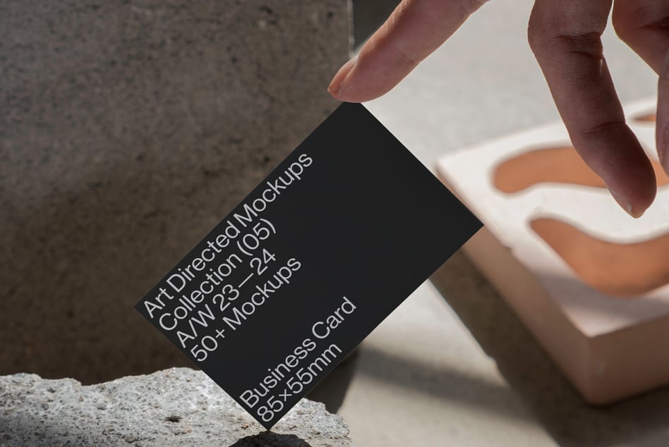 Hand holding black business card near orange ceramic vessels on concrete