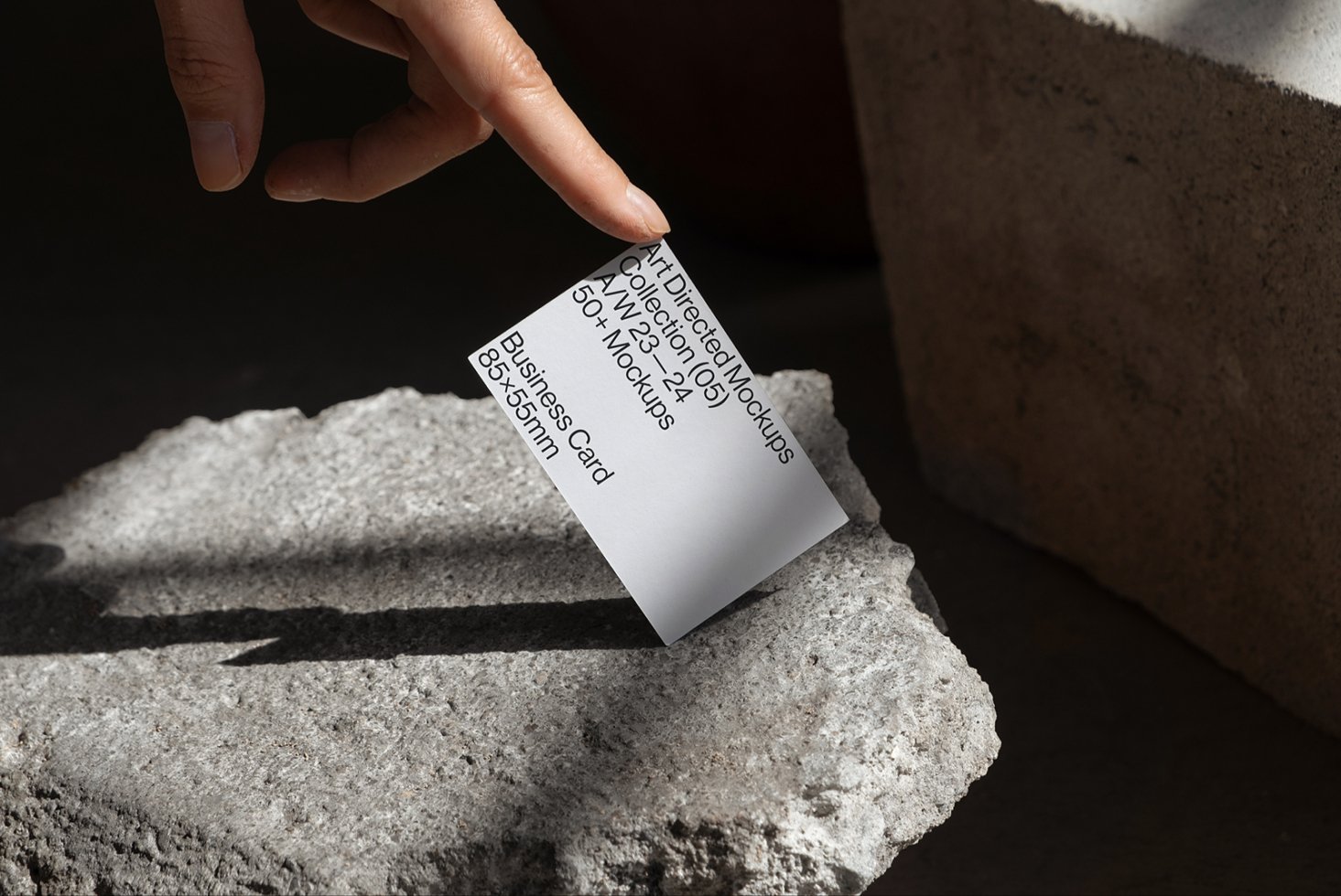 Hand holding a business card on a stone surface mockup. Ideal for showcasing 85x55mm business card designs. Perfect for design projects, templates.