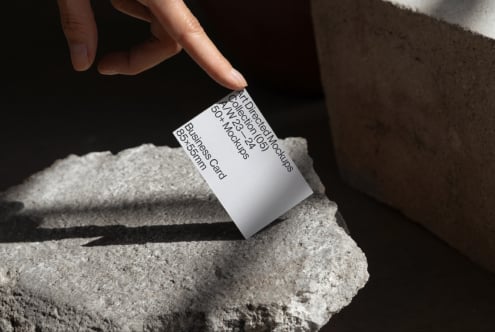 Hand holding a business card on a stone surface mockup. Ideal for showcasing 85x55mm business card designs. Perfect for design projects, templates.
