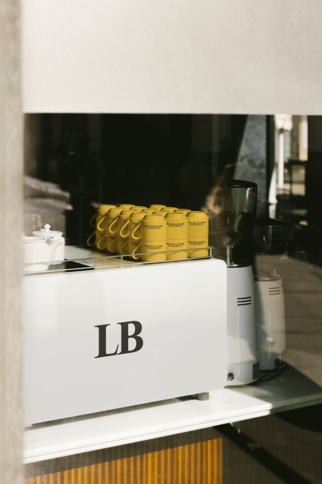 Coffee shop counter with white espresso machine LB logo yellow mugs displayed branding design mockup for cafes barista equipment interior inspiration
