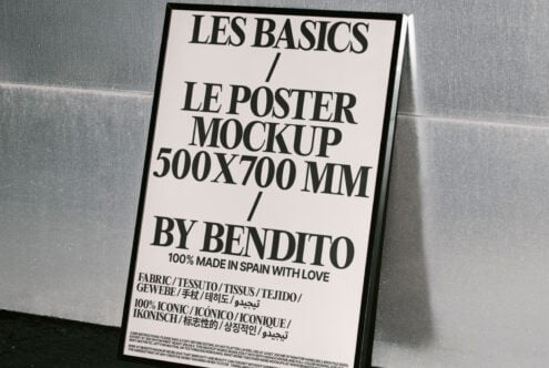 Poster mockup in black frame leaning against metallic wall. Text highlights size 500x700 mm. Ideal for graphic designers seeking minimalist templates.