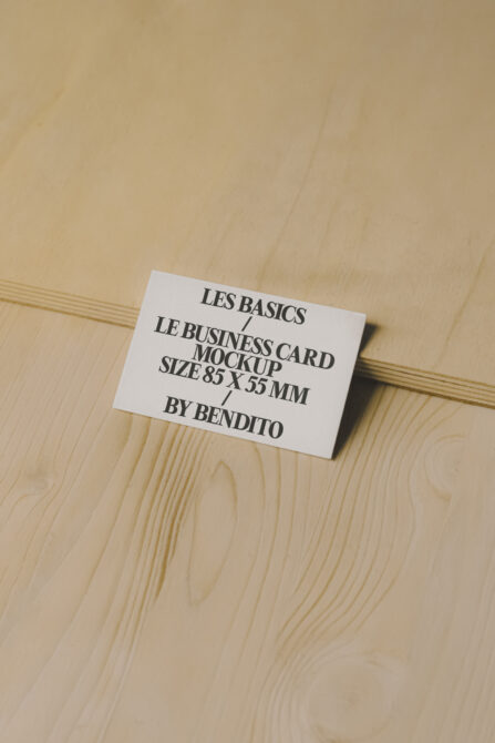 Business card mockup on a wooden surface featuring minimalist design in 85x55mm size ideal for branding presentations graphic design showcase.
