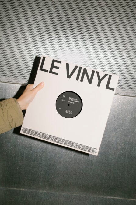 Hand holds a vinyl record mockup featuring bold typography. Ideal for graphic design projects, music branding, album cover templates, digital assets.