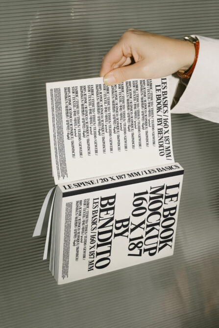 Cream hardcover book mockup held up displaying front cover with visible spine detail