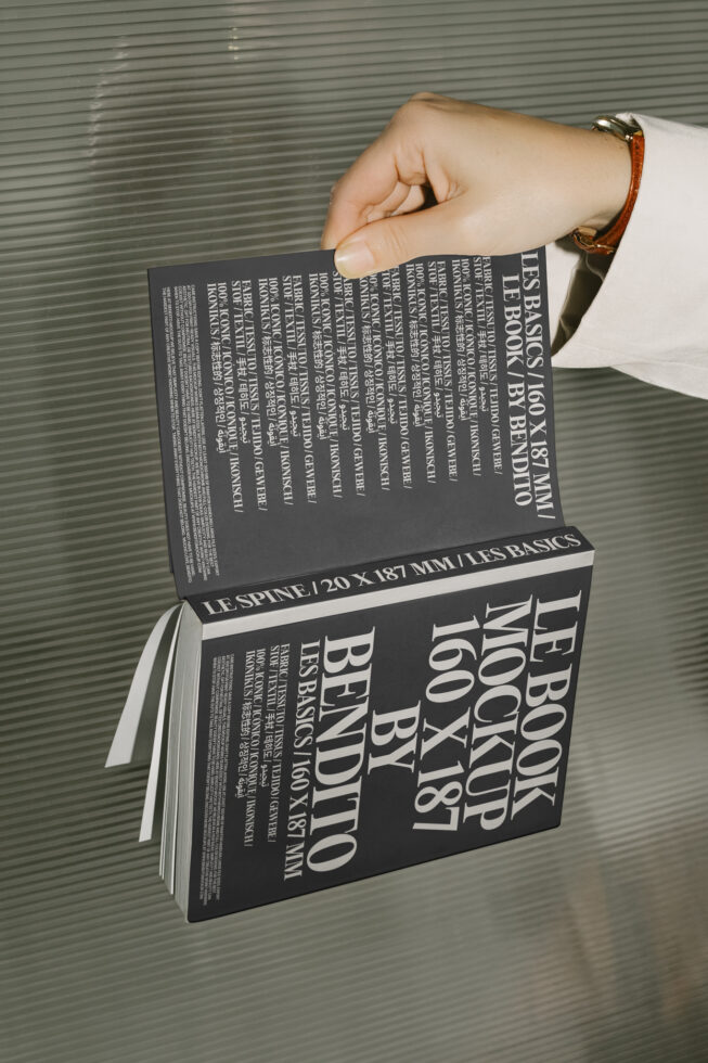 Hand holding an open book mockup against a textured background showcasing typography design, ideal for graphic designers seeking professional mockup templates.