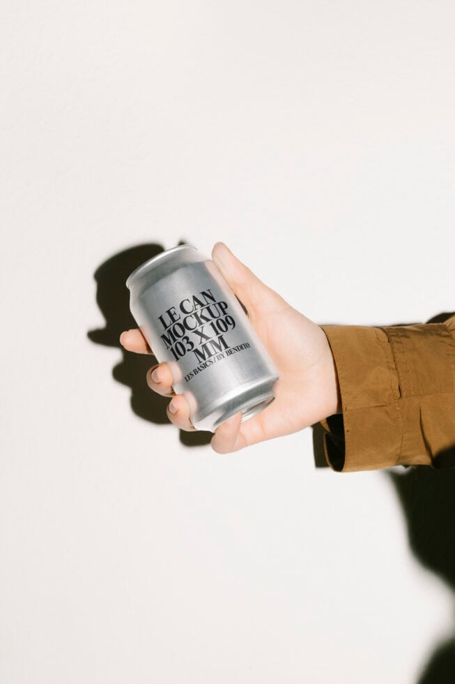 Hand holding a sleek aluminum can mockup with modern typography ideal for designers. Perfect for showcasing branding. Download graphic template.