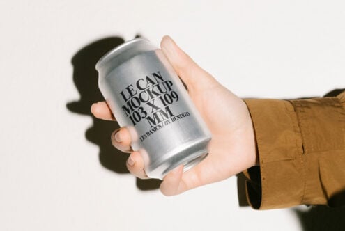 Hand holding a silver soda can mockup with bold typography design, perfect for designers. Can template for packaging design, branding, marketing projects.