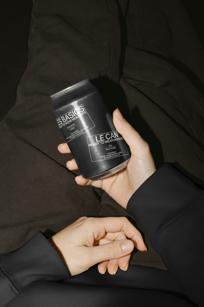Person holding a sleek black can mockup against dark clothing. High-quality product design mockup for designers. Ideal for branding presentations.