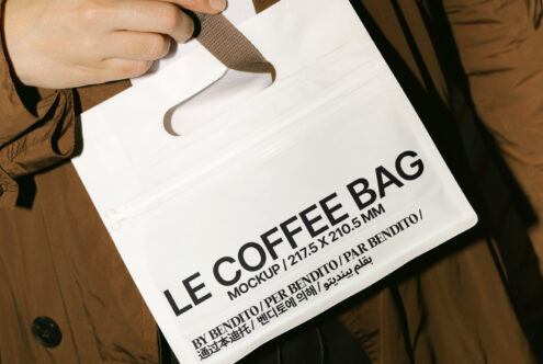 Hand holding white coffee bag mockup with text Le Coffee Bag by Bendito. Perfect for designers creating packaging graphics and mockup presentations.