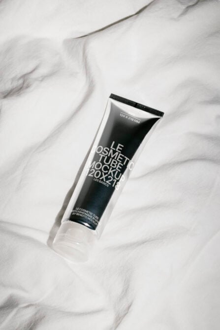 Clear cosmetic tube mockup on marble displaying dark label with product text overlay