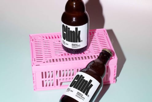 Glass bottles with bold text labels on pink crate minimalist design perfect for mockup projects product presentation and branding for designers