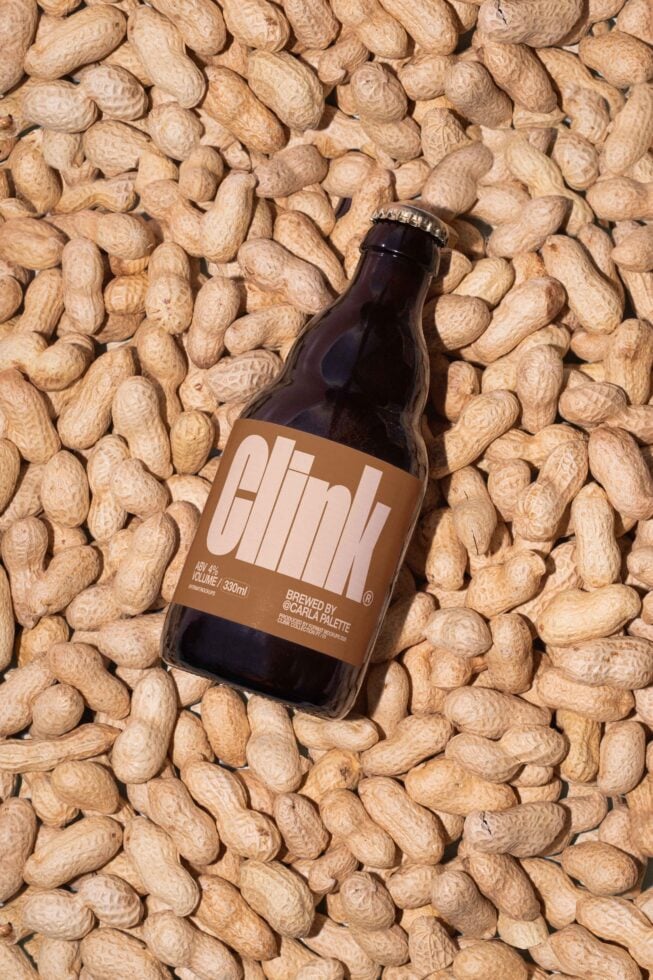 Bottle with minimalist label on peanuts background; suitable for beverage branding mockups; ideal for designers in need of packaging graphics; customizable.