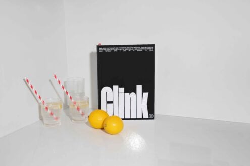 Stylish book with bold text stands beside lemons and glasses with red striped straws on a white surface perfect for designers clean mockup setup.