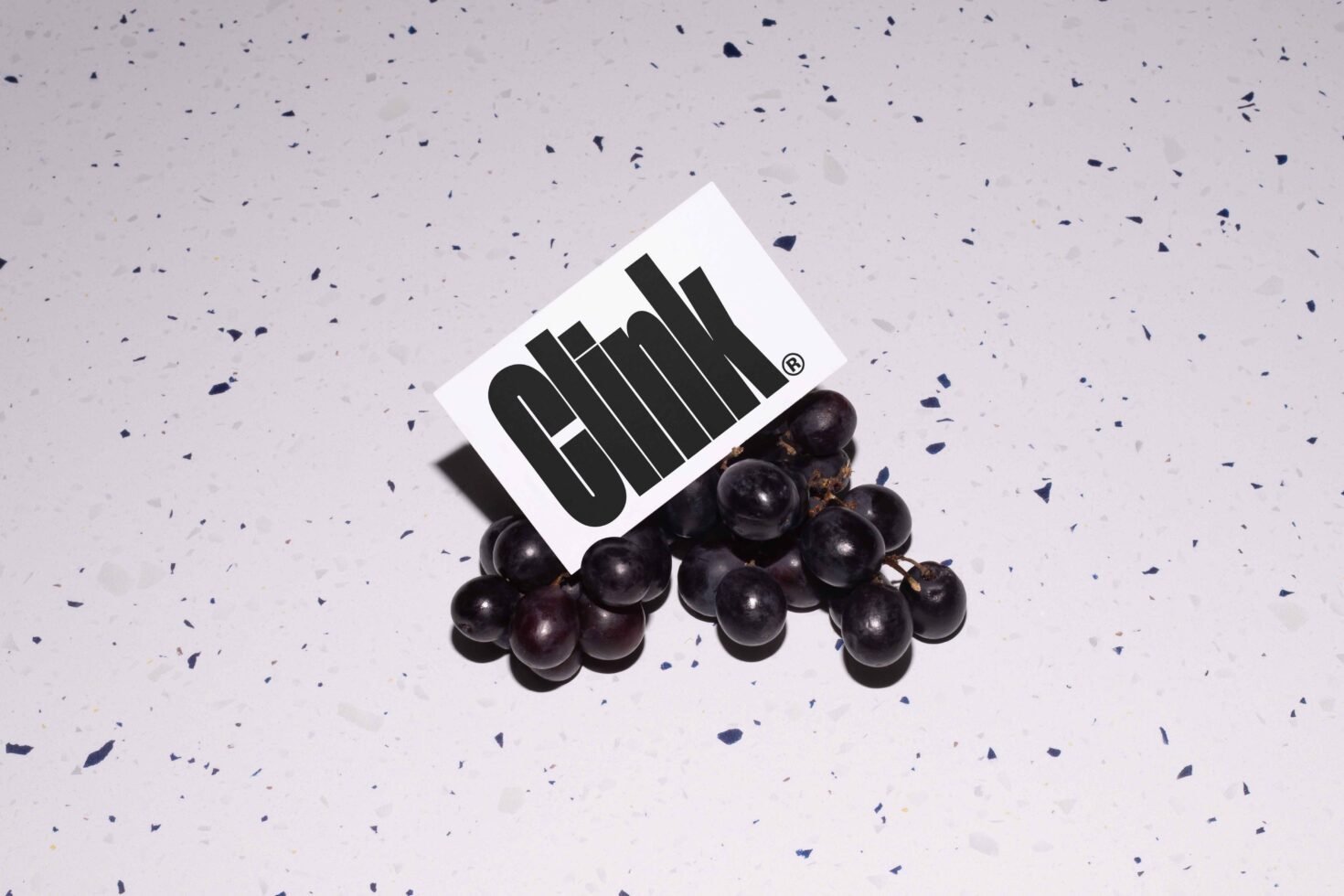Grapes with a card showcasing bold modern font Clink. Perfect for graphic design mockups and typography projects. Ideal for designers seeking unique assets.