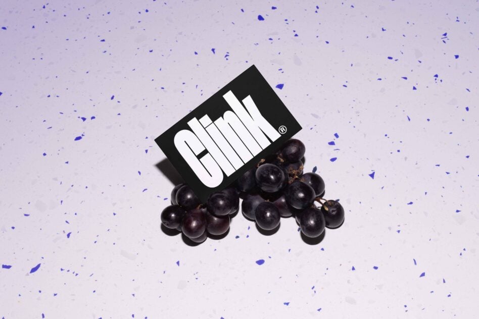 Black card with white text resting on dark grapes against speckled purple