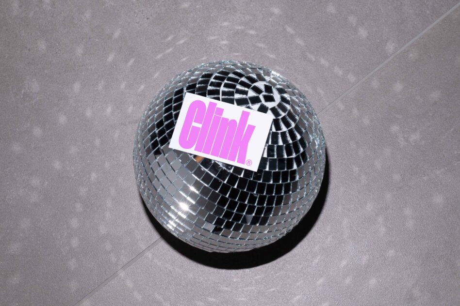 Metallic disco ball with bright magenta label on matte gray backdrop