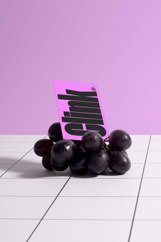 Mockup image with grapes and a bold pink card on a tiled surface. Ideal for graphic designers looking for unique templates or creative layouts.
