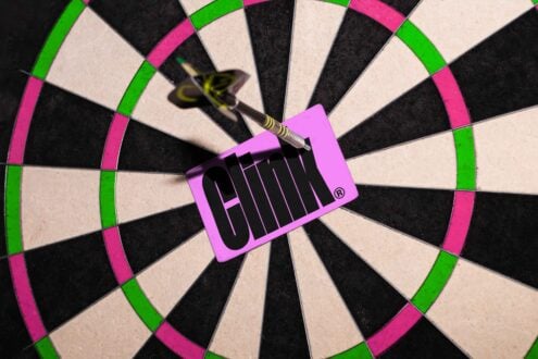 Dartboard with bullseye hit by dart and pink card, vibrant colors, perfect for digital graphic design resources, mockups, high impact visuals.