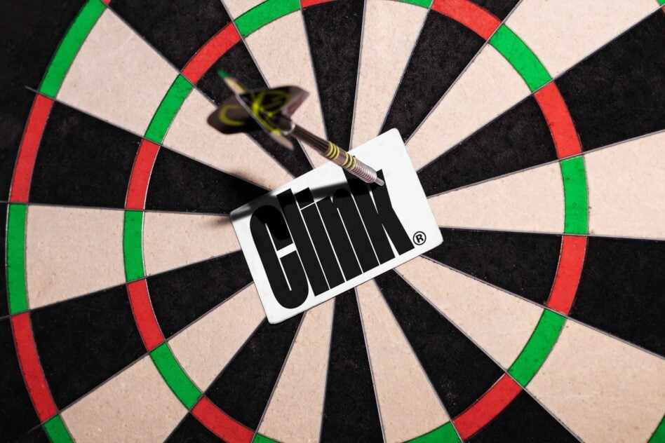 Dart with white label landing in center of traditional red, green, black dartboard