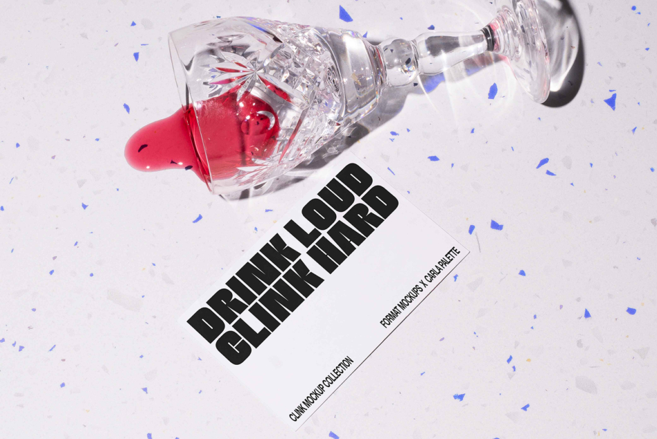Overhead shot of tipped cocktail glass with red liquid, confetti scattered around, next to black text label on white background