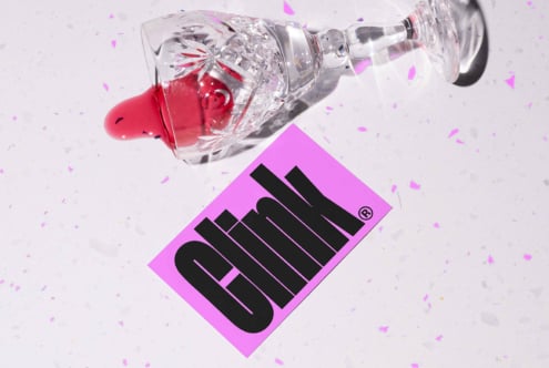Crystal glass with red liquid tipped over beside a pink card with bold black text Clink on confetti background. Keywords: graphics, mockup, design asset.
