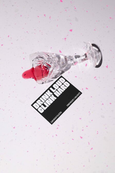 Spilled cocktail glass with pink confetti on white textured surface