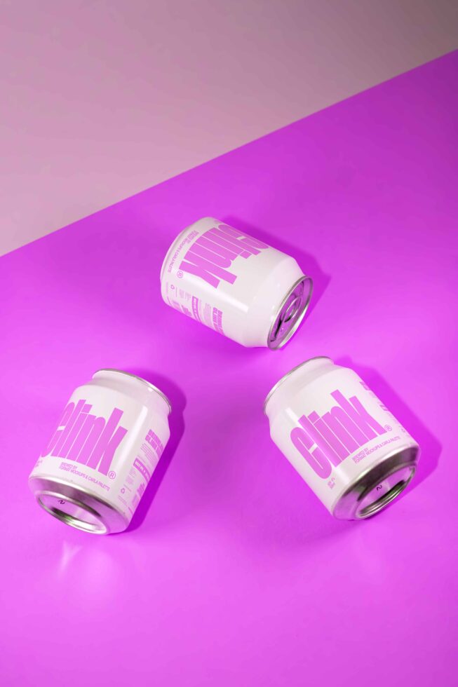Three soda can mockups with pink labels on a vibrant pink background. Ideal for packaging design projects. High-quality graphic template for designers.