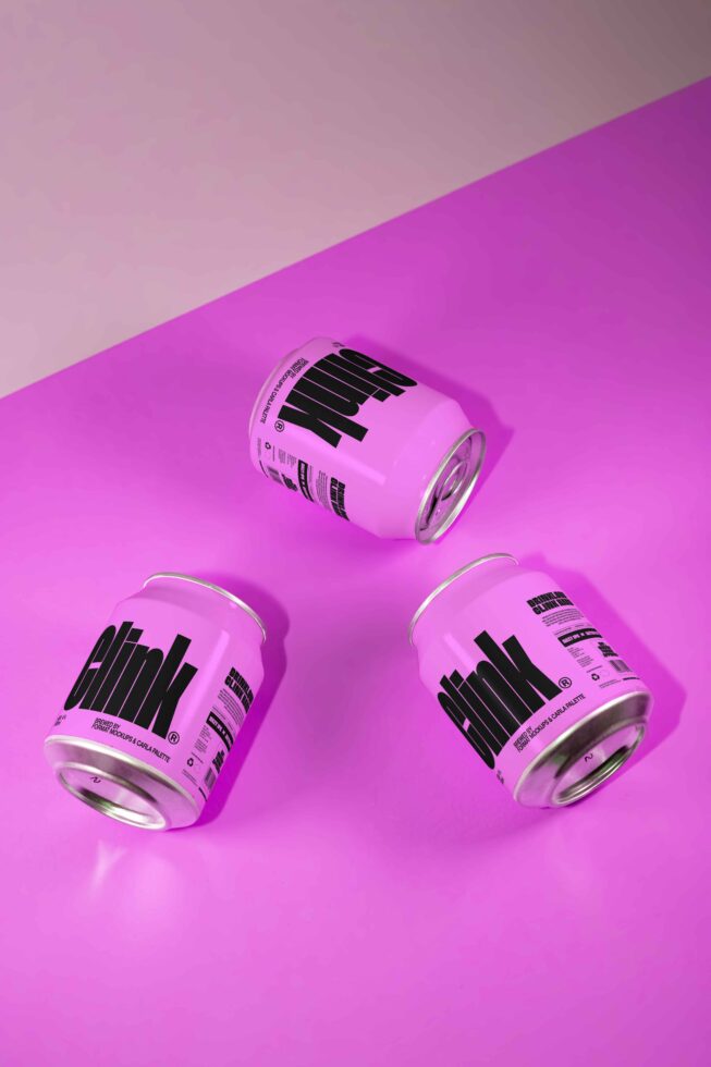 Three pink soda can mockups lie on a vibrant pink surface with bold text design perfect for designers seeking creative beverage packaging templates.