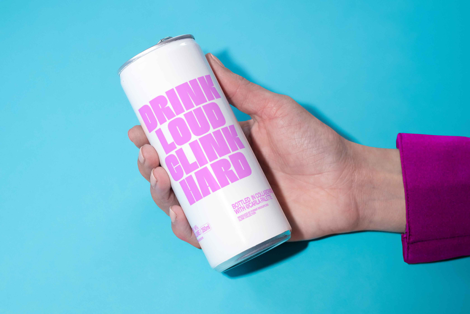 Hand holding white beverage can with bold pink text on turquoise background