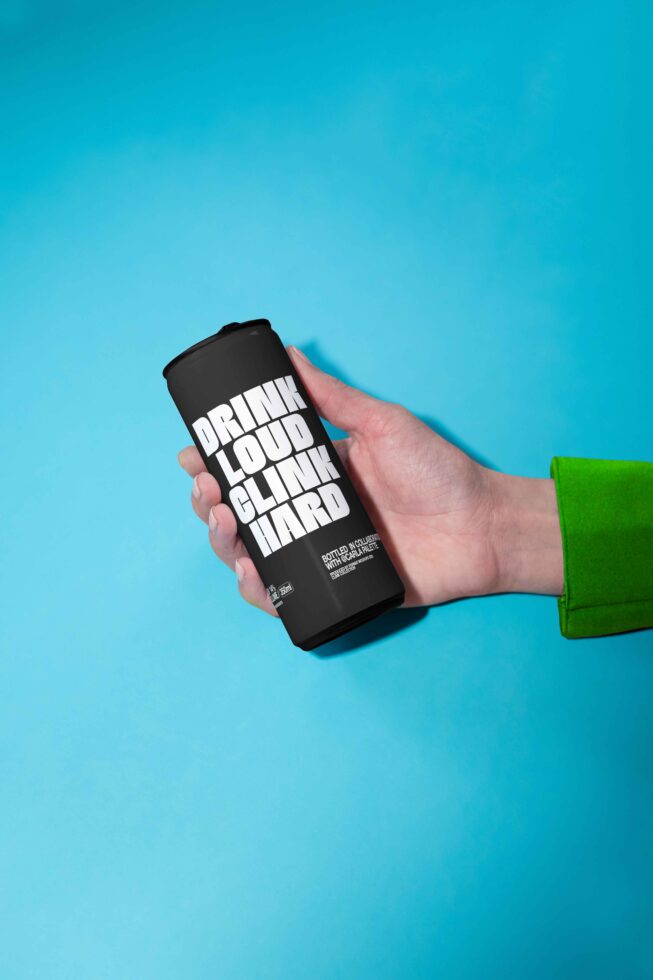 Mockup of a hand holding a black can with bold white typography on a blue background, ideal for designers in branding and packaging design projects.