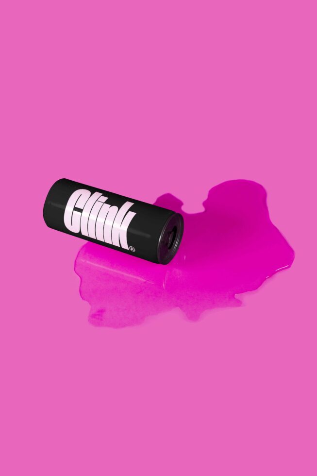 Black beverage can with pink horizontal lines on magenta background puddle