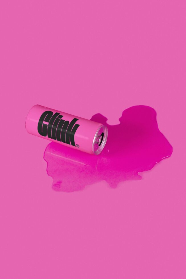 Hot pink beverage can with black horizontal lines on magenta background puddle
