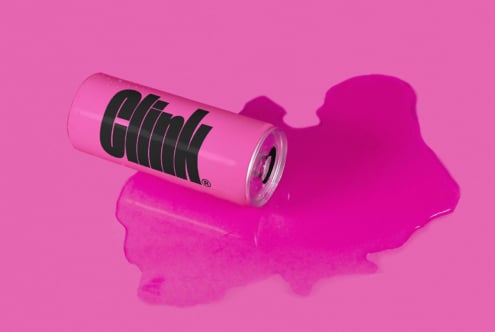 Pink soda can design mockup with bold black text on a vibrant pink background and spilled liquid perfect for branding packaging graphics templates.