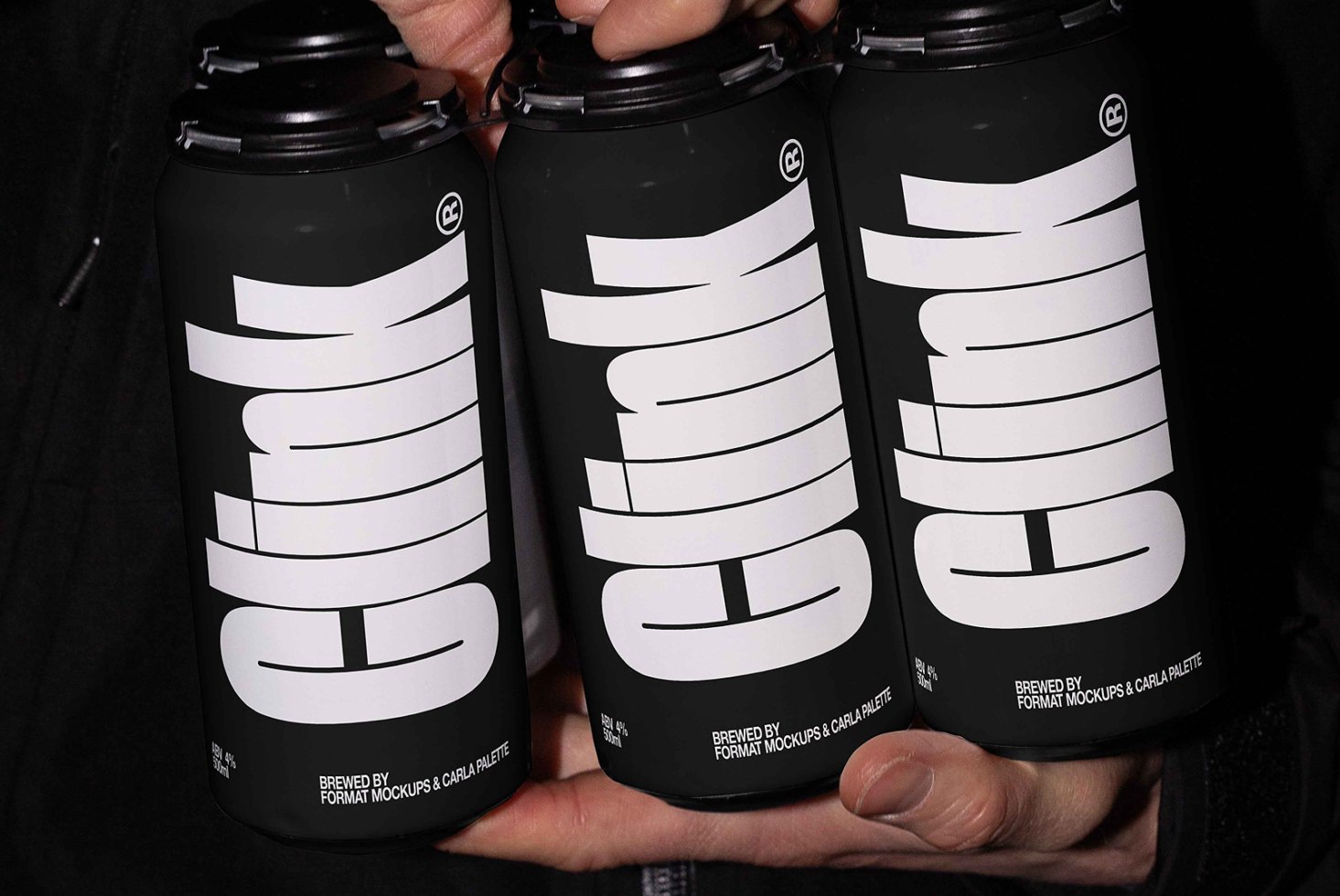 Close-up of three black beverage cans with bold white text held in hand. Ideal for product mockups, packaging design, and branding projects.