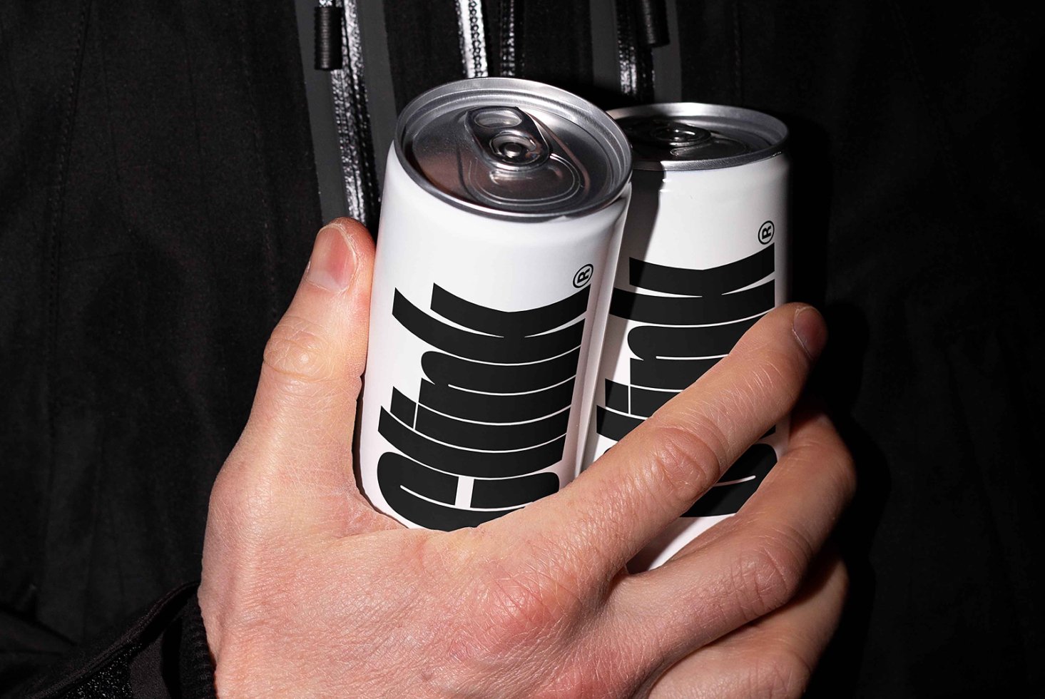 Close-up of a hand holding two white soda cans with bold typography. Perfect for branding mockups, packaging design, or graphic design projects.