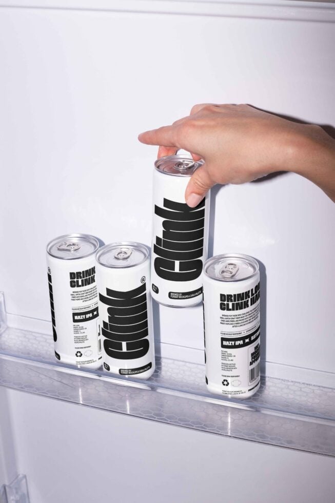 Hand placing sleek beverage can with bold text in fridge. Ideal for mockup designs showcasing modern branding. Designers resource. Mockups SEO.