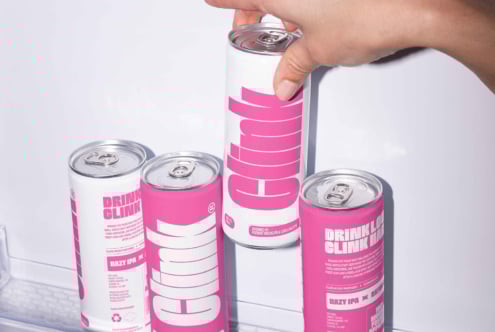 Hand reaches for pink beverage cans in refrigerator perfect for branding or packaging needs in mockup design projects with vibrant typography SEO