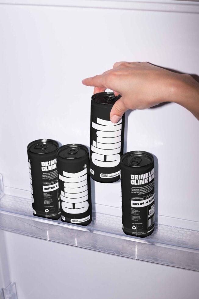 Hand arranging sleek black canned drinks in fridge. Modern beverage packaging mockup. Ideal for designers seeking minimalistic product presentation.