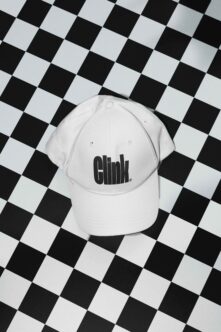 White baseball cap with black embroidered logo on black checkered surface