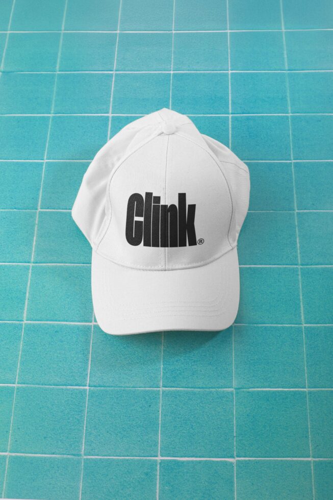 White baseball cap with black logo on turquoise tile background flat lay