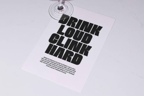 Flyer on marble table with bold black font that reads Drink Loud Clink Hard, ideal for designers seeking typography inspiration and graphic templates.