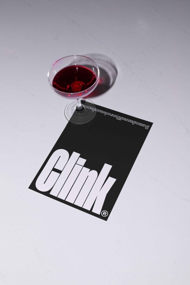 Elegant mockup featuring a glass with red liquid casting a shadow over a card showing the word Clink. Perfect for designers seeking creative inspiration.