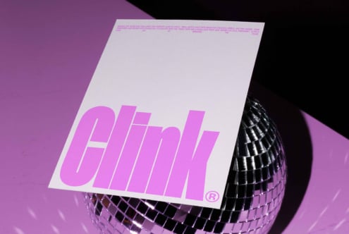 Pink typography on a sleek monochrome poster resting on a reflective disco ball, perfect for modern graphic design mockup and creative templates.