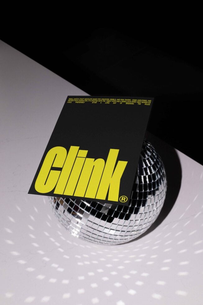 Mockup of a black card with bold yellow text resting on a disco ball. Ideal for graphic designers. Keywords: Mockups, Templates, Design Resources.